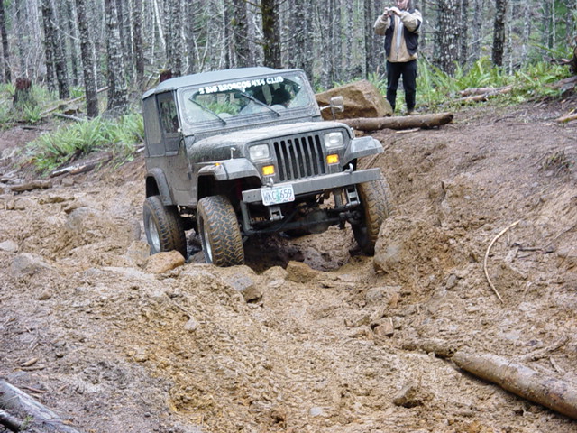 1995 Jeep Wrangler navigating a steep, muddy off-road trail