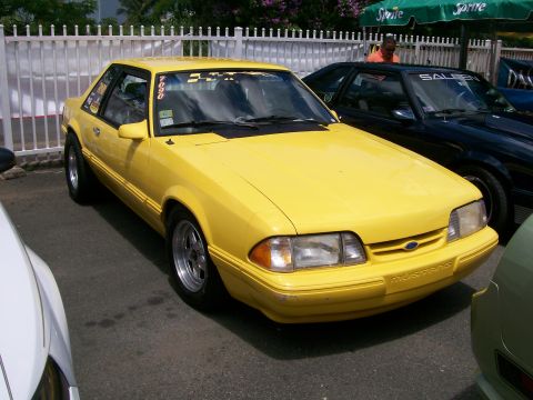 2001 Ford Mustang - A bright yellow Ford Mustang coupe is parked at an outdoor event. Another Mustang is visible behind it.