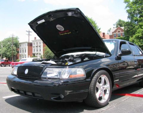 2003 Mercury Marauder - A black 2003 Mercury Marauder is parked with its hood up, revealing the engine and a 'Supercharged' decal on the underside of the hood.