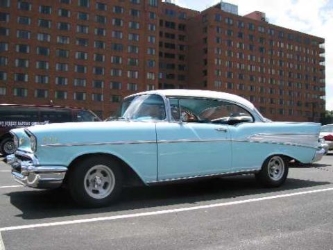 2003 Mercury Marauder - A light blue 1957 Chevrolet Bel Air coupe is parked in a lot with a brick building in the background.