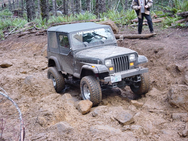 1995 Jeep Wrangler climbing a muddy hill, license plate WHC659