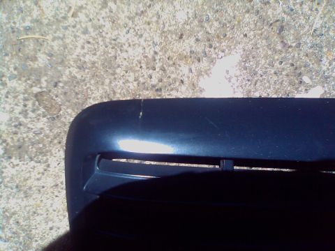 2000 Ford Crown Victoria - A close-up view of a car's front grille, showing horizontal slats and minor surface damage.