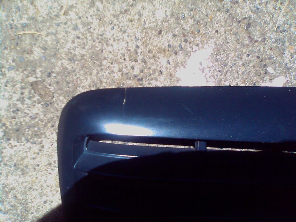 Close-up of a dark blue car grille with horizontal slats. Some scratches are visible on the upper surface