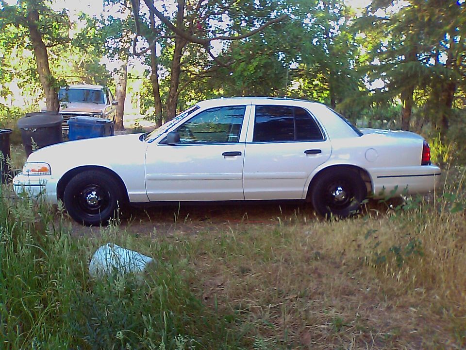 2000 Ford Crown Victoria parked on grass, side view. Another vehicle is visible in the background