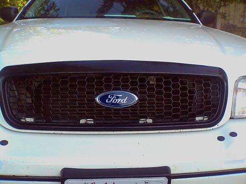 2000 Ford Crown Victoria - Front view of a white 2000 Ford Crown Victoria showing its distinctive honeycomb grille and Ford emblem.