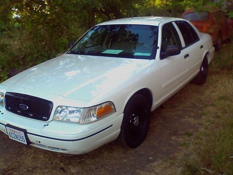 2000 Ford Crown Victoria - This white 2000 Ford Crown Victoria is seen from a 3q-front angle, with another vehicle partially visible behind it.