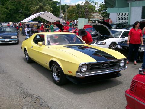 2001 Ford Mustang - A yellow 1971 Ford Mustang is displayed at an outdoor car show with other vehicles and spectators.
