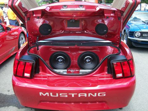 2001 Ford Mustang - The rear of a red 2001 Ford Mustang is shown with its trunk open, revealing a custom sound system.
