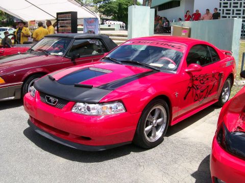 2001 Ford Mustang - A red Ford Mustang is parked at an outdoor event, with another Mustang visible to its left.