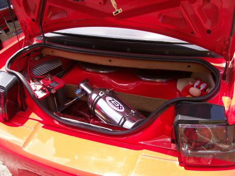 2001 Ford Mustang - The trunk of a red car is open, revealing custom audio equipment and a nitrous oxide system.