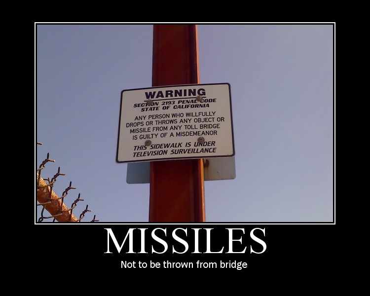 Warning sign on a pole about dropping objects from a bridge, with text about California penal code and surveillance