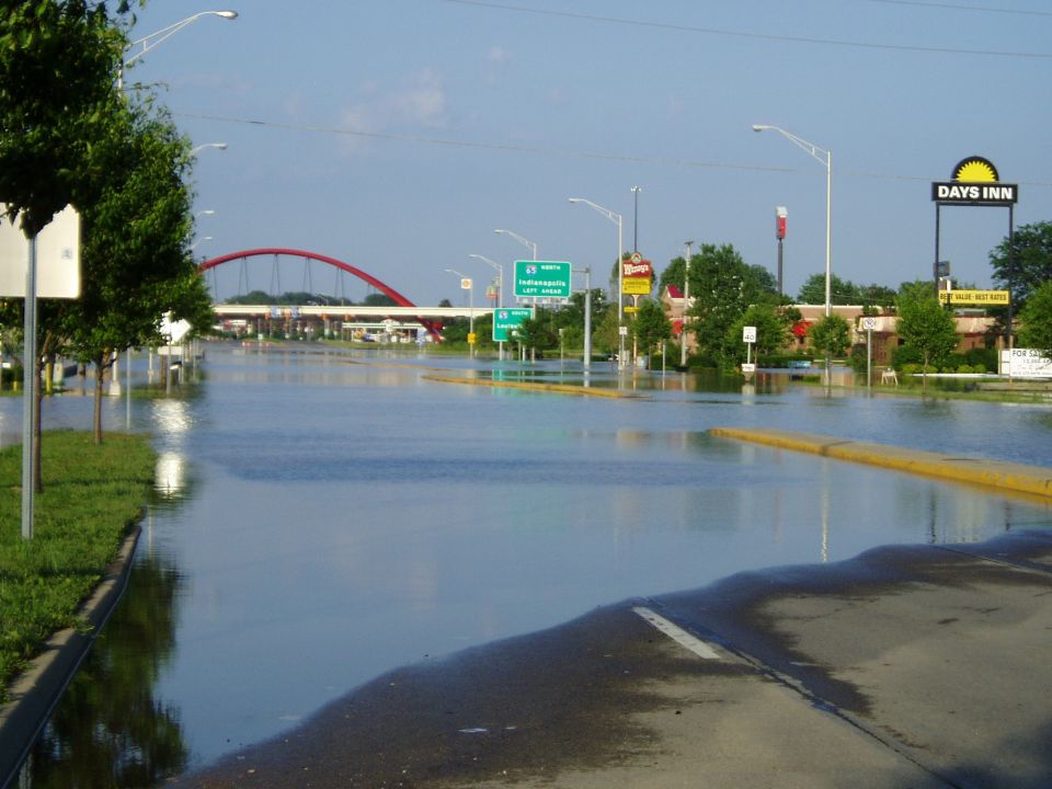 Flooded road with a red arched bridge in the distance and a Days Inn sign
