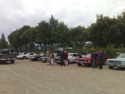 1991 Ford Crown Victoria - A gathering of classic cars, including a red 1969 Ford Mustang, with several people observing.