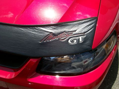 2001 Ford Mustang - Close-up of a red Ford Mustang GT's front end, highlighting the hood bra and GT badging.