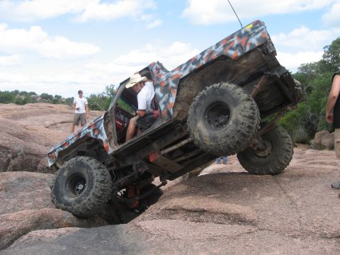 1979 Ford Bronco - This heavily modified truck is navigating a challenging rocky terrain with its tires at extreme angles.