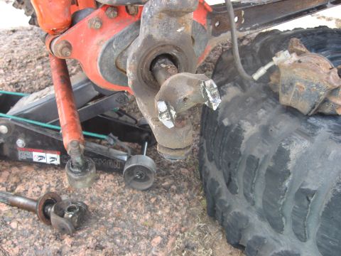 1979 Ford Bronco - A damaged vehicle suspension part is shown, with a tire and jack nearby, suggesting repair work.