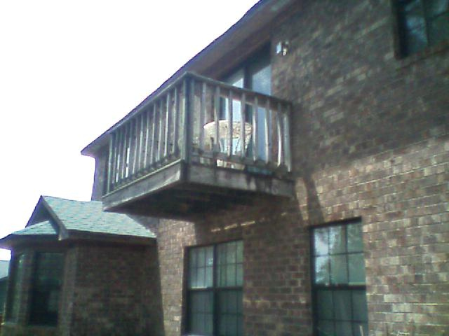 Second-story wood balcony deck on a brown brick house