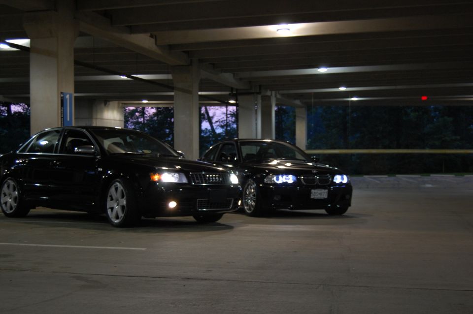 Black Audi sedan and black BMW sedan parked in a garage