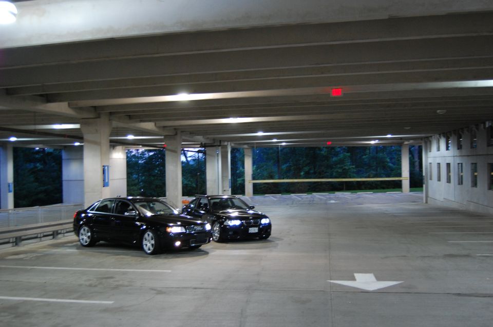 Two black sedans in a parking garage, one in foreground