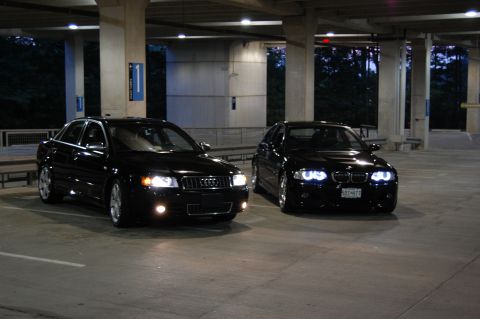 2002 BMW M3 - Two black sedans, an Audi and a BMW, are parked in a dimly lit garage.