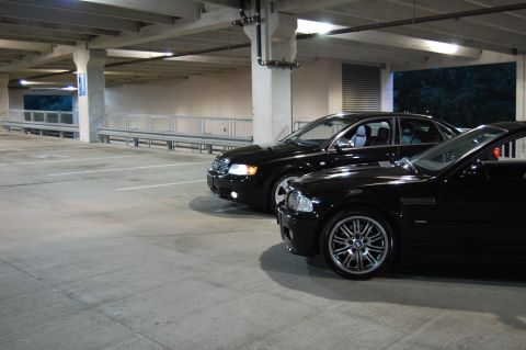 2002 BMW M3 - A black 2002 BMW M3 is parked next to a black Audi sedan in a dimly lit parking garage.