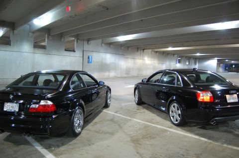 2002 BMW M3 - Two black performance sedans, a BMW M3 and an Audi S4, are parked side-by-side in a dimly lit garage.