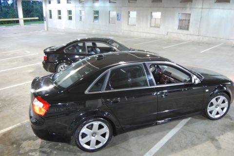 2002 BMW M3 - Two black sedans are parked side-by-side in a parking lot.