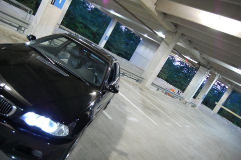 2002 BMW M3 - A black BMW M3 is parked in a multi-level concrete parking garage with trees visible in the background.