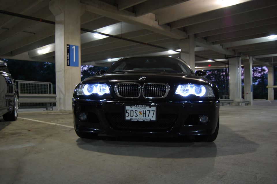 Black 2002 BMW M3 sedan with halo headlights parked in a garage