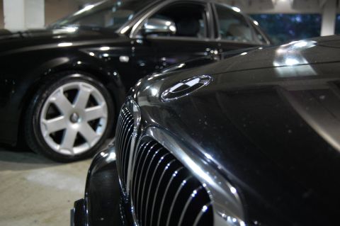 2002 BMW M3 - Two black cars are parked closely together, with the front of one vehicle dominating the foreground.