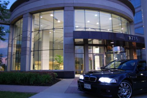 2002 BMW M3 - A black 2002 BMW M3 is parked in front of a building with large glass windows.