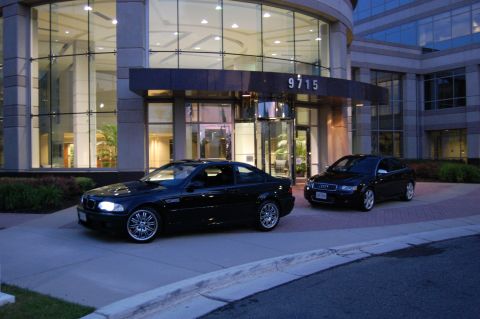 2002 BMW M3 - Two black cars, a BMW M3 coupe and an Audi sedan, are parked outside a building with the address 9715 visible.