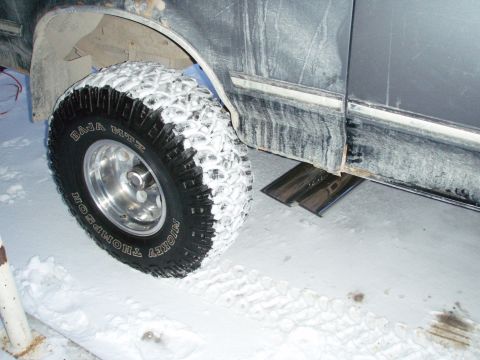 1992 Ford Bronco - A vehicle with Mickey Thompson Baja MTZ tires sits in the snow, with the front fender and side panel visible.
