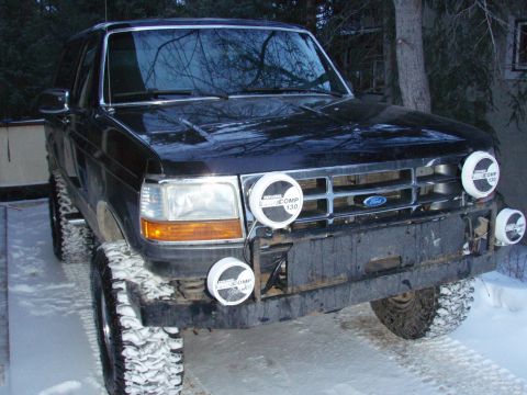 1992 Ford Bronco - A black Ford Bronco sits in the snow, equipped with auxiliary lights for off-road use.