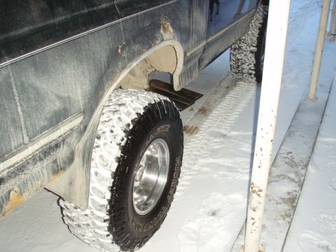 1992 Ford Bronco - A 1992 Ford Bronco's rear wheel is covered in snow, showing its off-road tires and mud flaps.