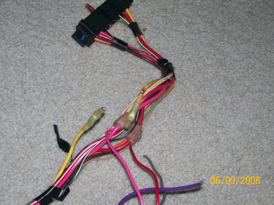 Automotive wiring harness with black connector and colored wires on carpet