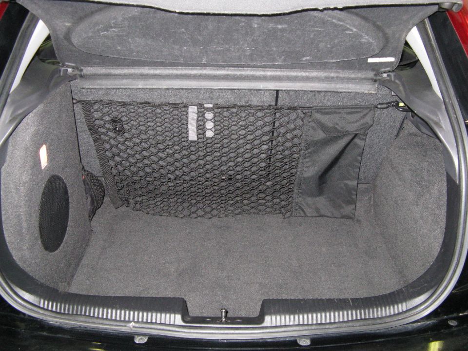 Gray carpeted hatchback trunk with black cargo net and side storage pocket