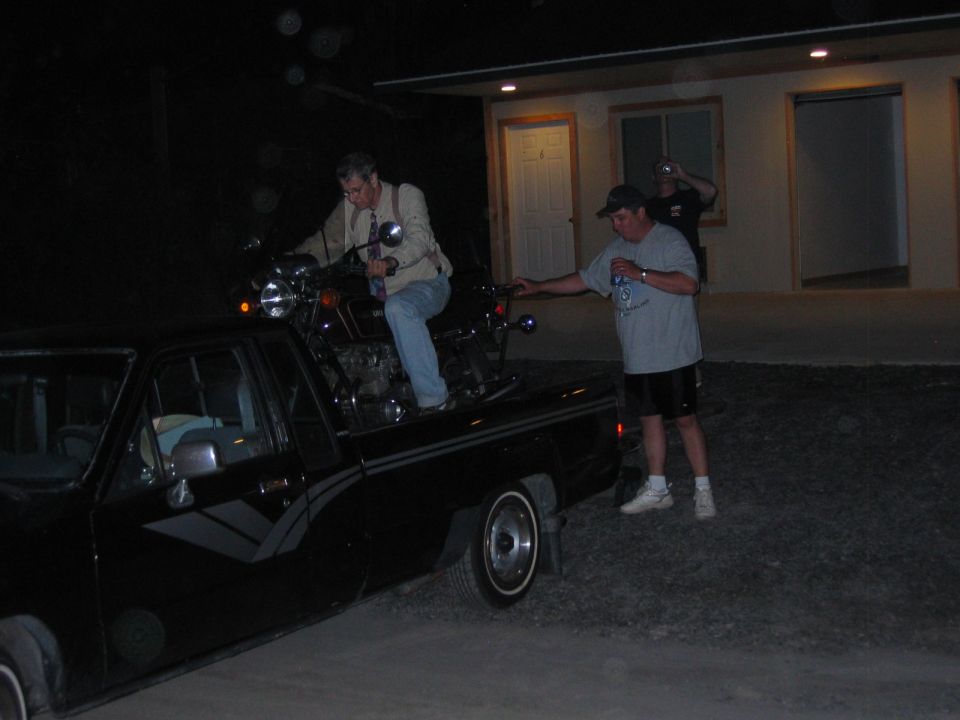 Motorcycle loaded onto the bed of a black pickup truck at night