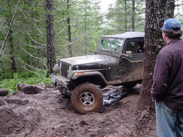 1995 Jeep Wrangler on a muddy trail with a person watching