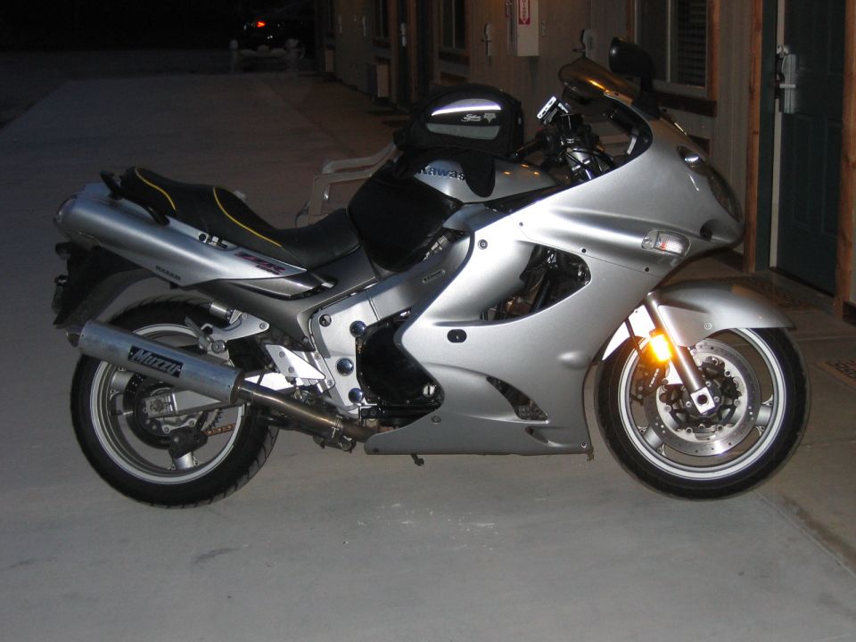 Silver sport motorcycle with black seat and saddlebag, parked on concrete