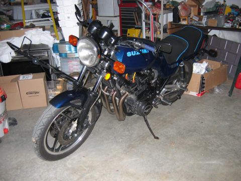 1985 Ford LTD Crown Victoria - A blue Suzuki motorcycle is parked in a cluttered garage, showing its engine and front wheel.