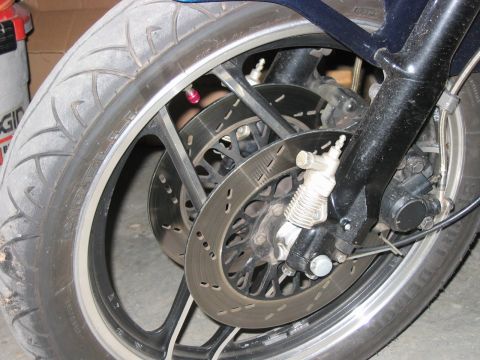 1985 Ford LTD Crown Victoria - Close-up view of a motorcycle's front wheel, its dual disc braking system and alloy rim.