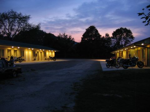 1985 Ford LTD Crown Victoria - Several motorcycles are parked in front of a motel with lights on at dusk.