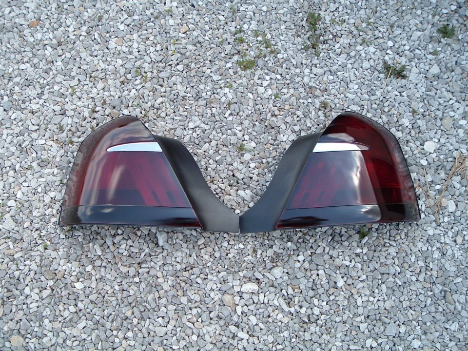 Pair of smoke-tinted taillight lenses laid out on gravel after tinting