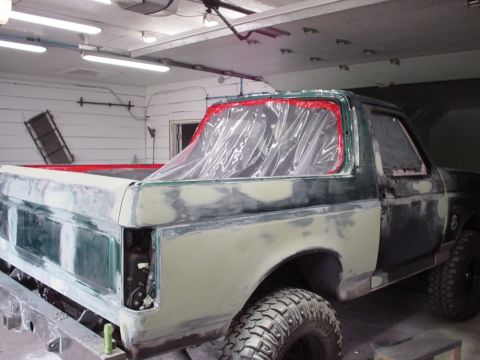 1996 Ford Bronco - Ford Bronco undergoing body repair, showing extensive body filler and primer application on the rear section.