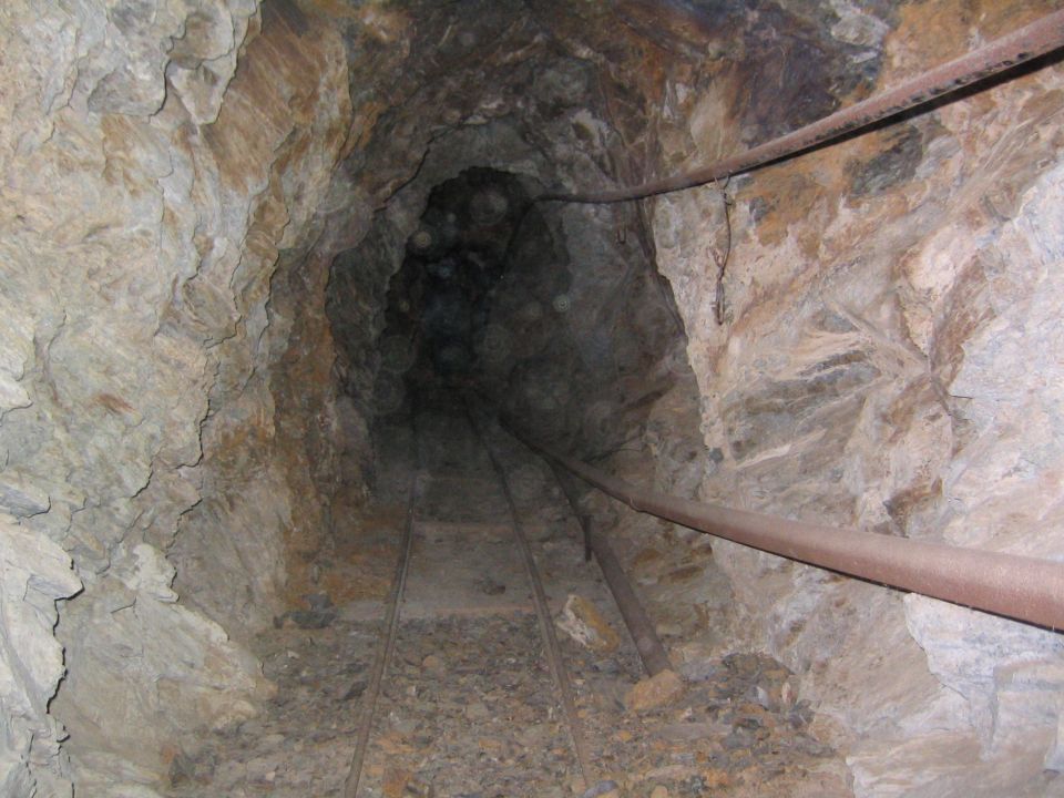 Underground mine tunnel with rail tracks and rocky walls