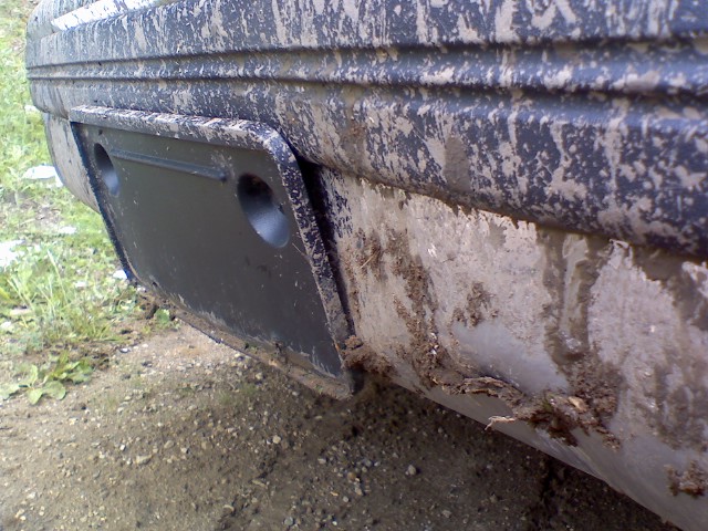 Mud-caked lower rear body and tow hitch area of a dark vehicle