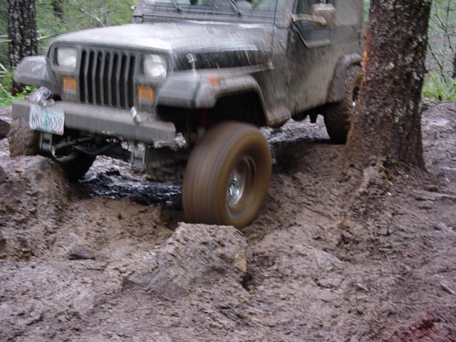1995 Jeep Wrangler navigating a muddy trail with front wheel turned