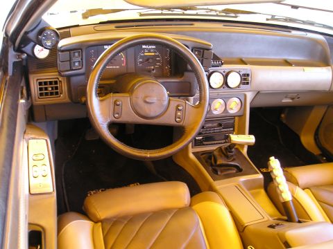 2001 Ford Mustang - The interior of a car shows tan leather seats, aftermarket gauges, and a McLaren speedometer, indicating a modified vehicle.
