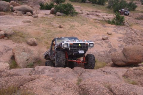 1979 Ford Bronco - A modified 1979 Ford Bronco navigates a rocky terrain, with another truck visible in the background.